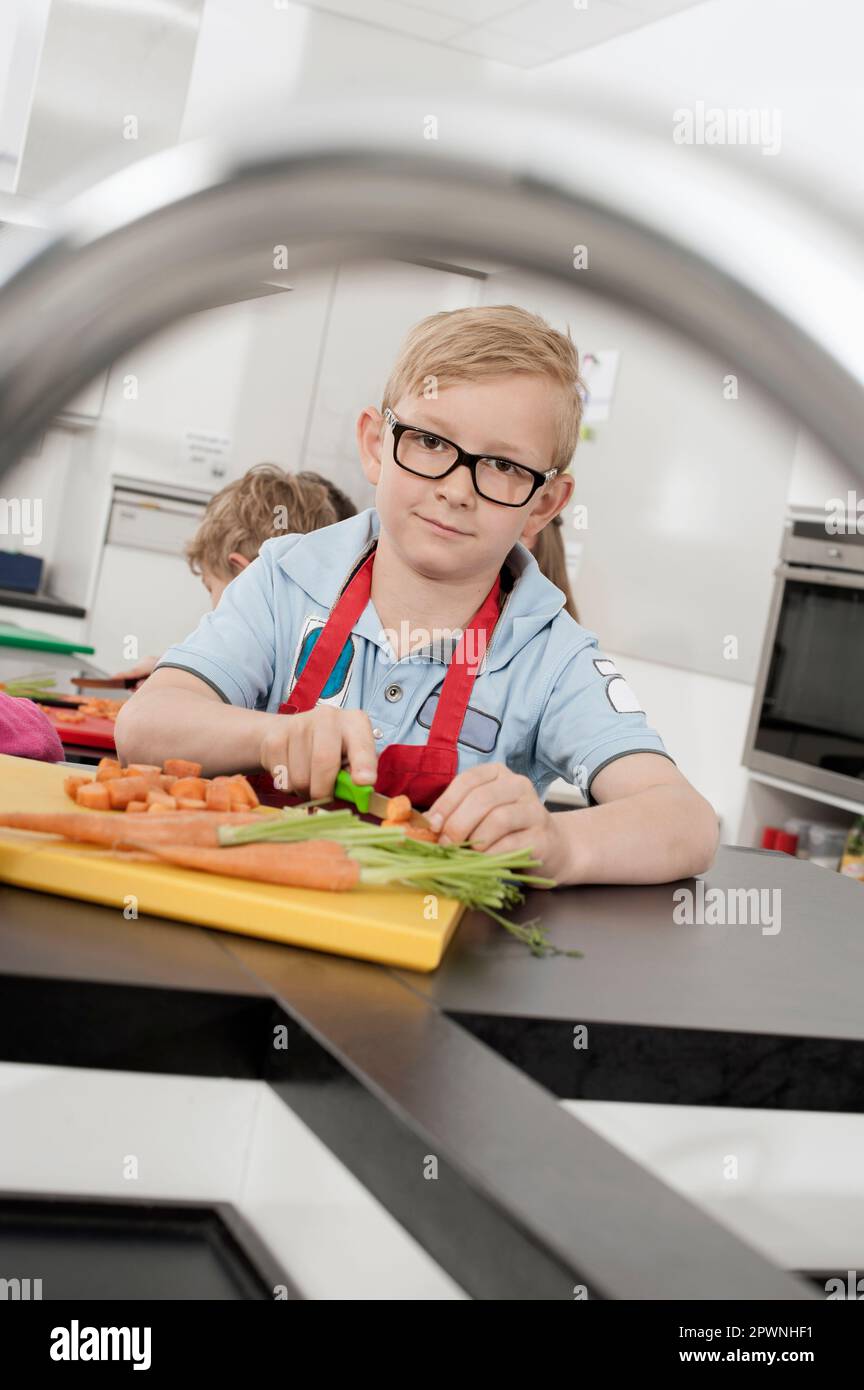 Due scolari che tagliano verdure in classe economica domestica, Baviera, Germania Foto Stock