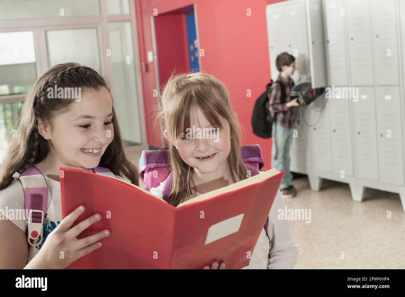 Due studentesse che leggono un libro nel corridoio vicino agli armadietti, Baviera, Germania Foto Stock