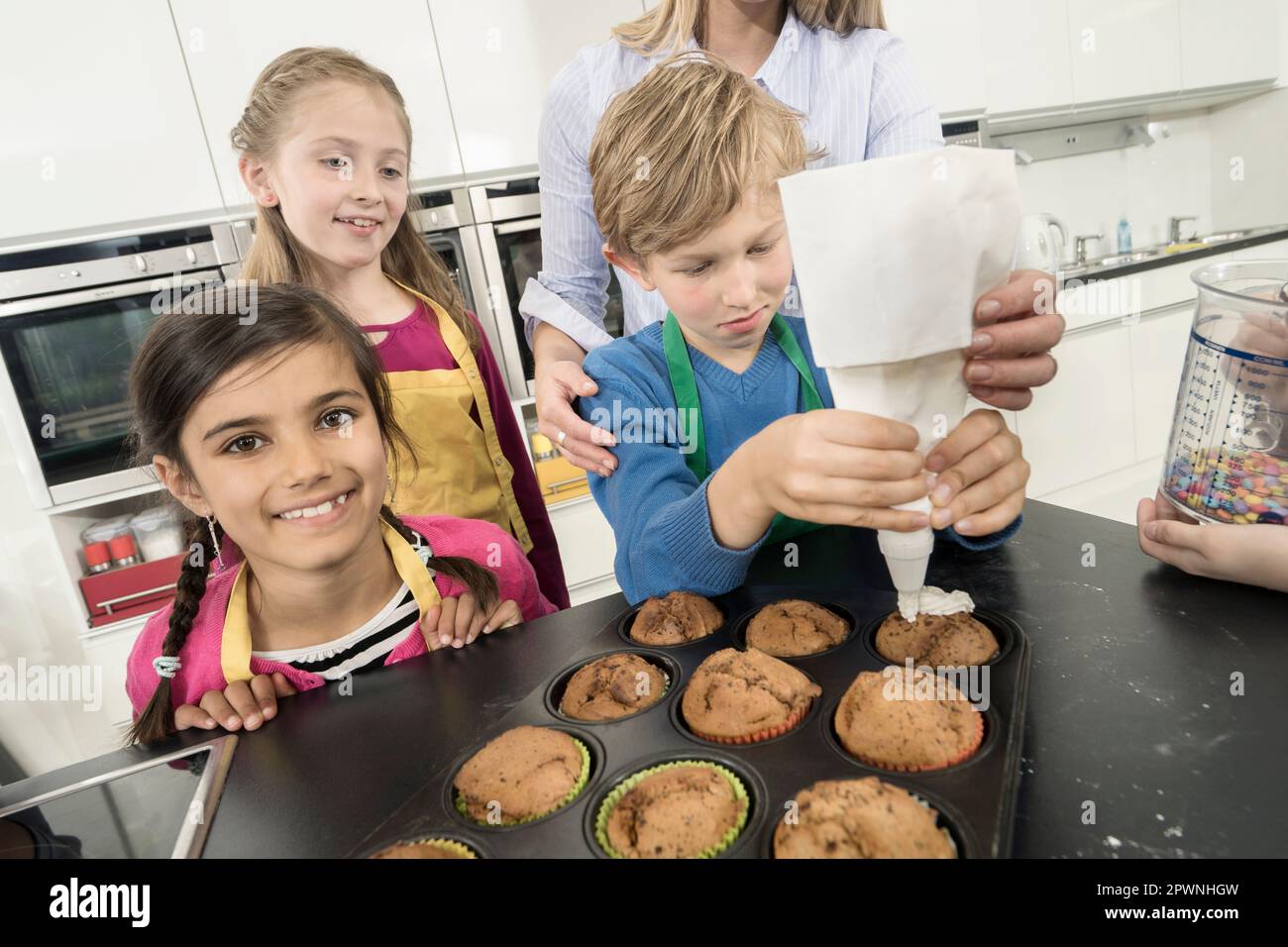 La glassa del ragazzo di scuola sui muffin con il sacchetto della glassa nella lezione domestica di economia, Baviera, Germania Foto Stock