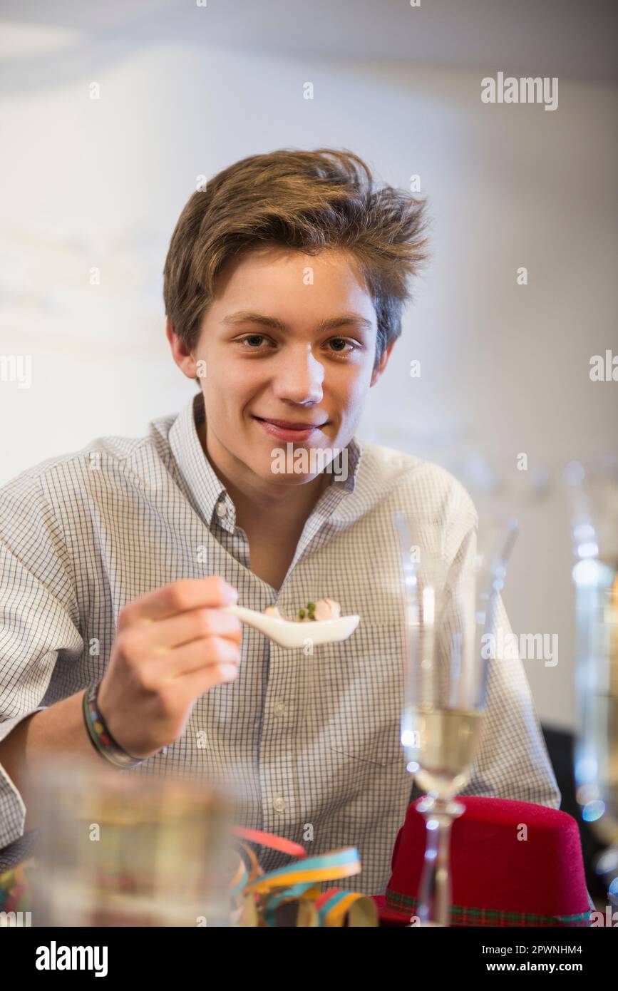 Ragazzo adolescente che mangia cibo alla festa di compleanno Foto Stock