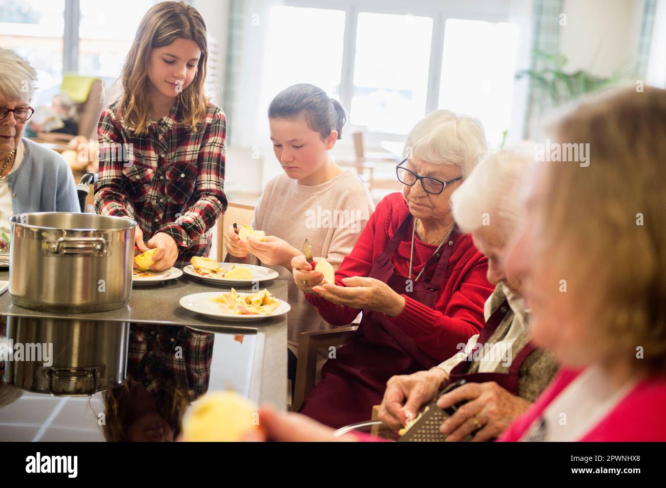 Donne anziane con ragazze che sbucciano la mela a casa di riposo Foto Stock
