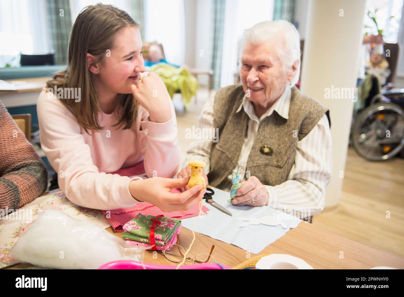Donna anziana con ragazza che tiene il pulcino a uncinetto fatto a mano a riposo a casa Foto Stock
