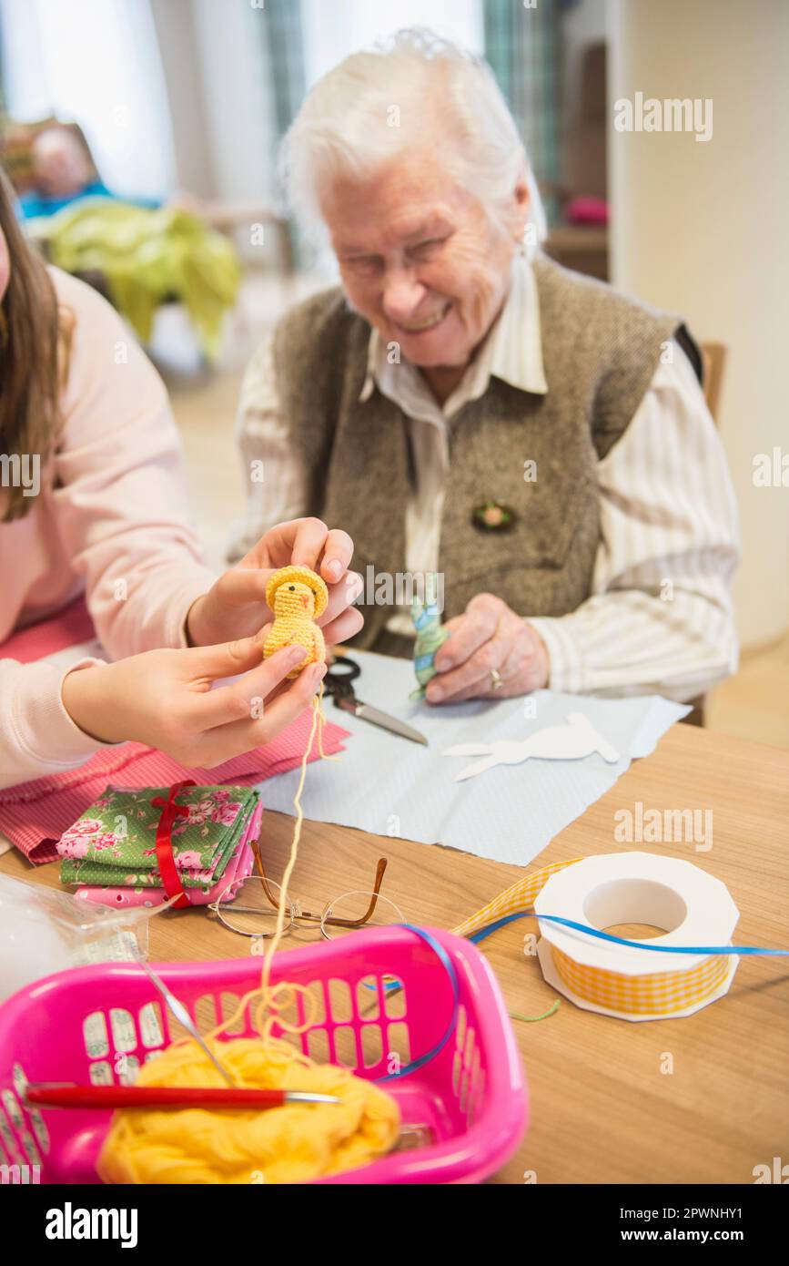Donna anziana con ragazza che tiene il pulcino a uncinetto fatto a mano a riposo a casa Foto Stock