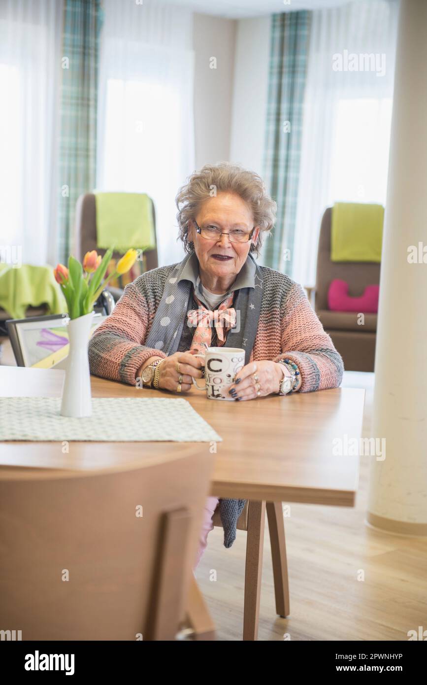 Donna anziana con caffè a casa di riposo Foto Stock