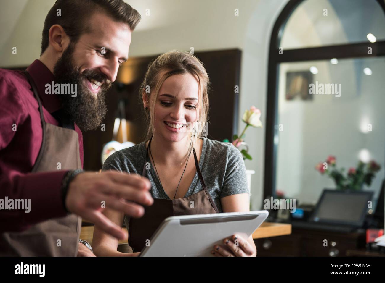 I giovani proprietari discutano mentre tengono un tablet al ristorante Foto Stock