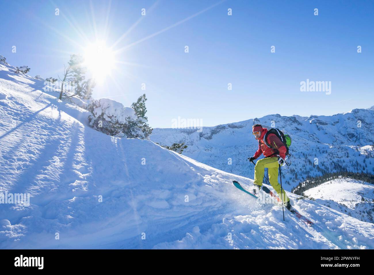 Sciatore che sale su una montagna innevata Foto Stock