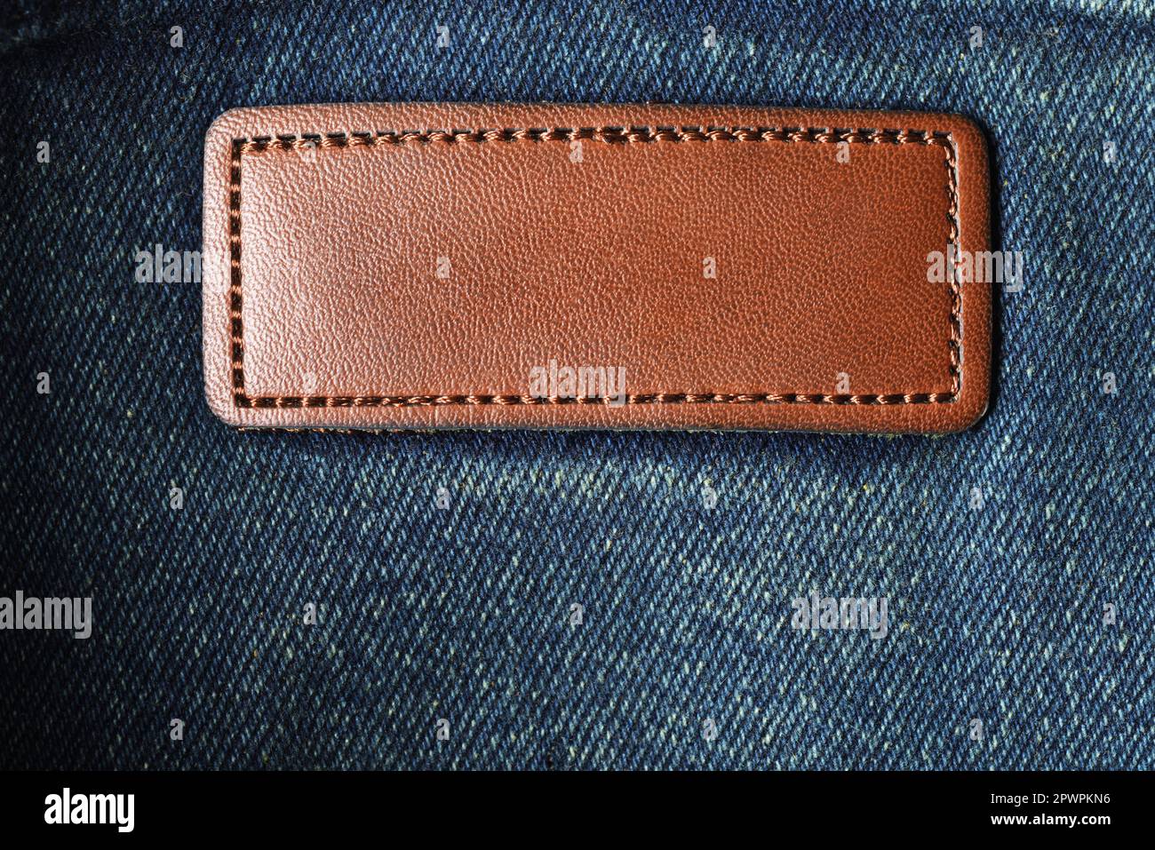 Etichetta in pelle marrone vuota sul panno in tessuto denim jeans scuro. Foto Stock
