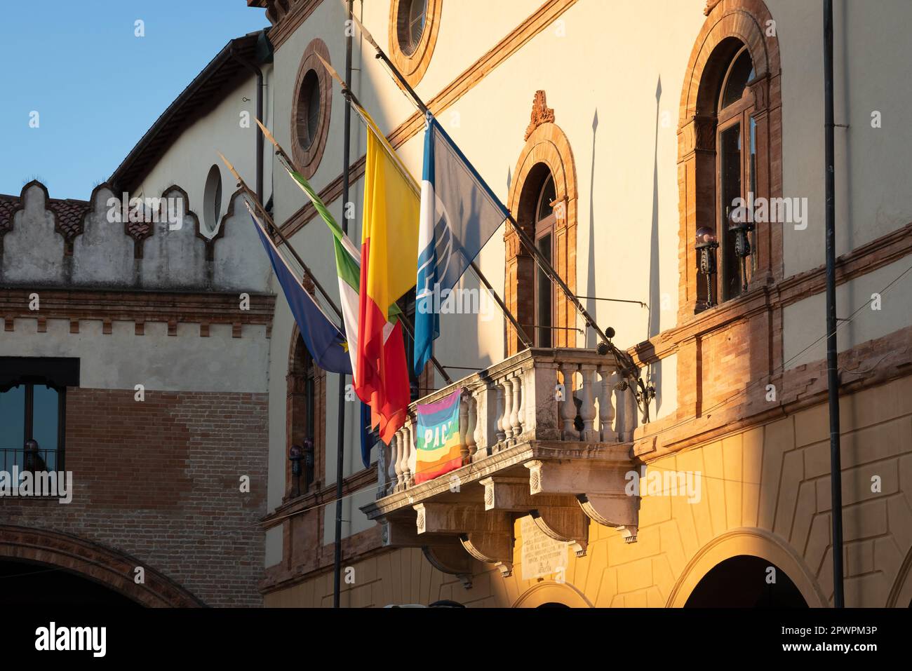 Vista laterale della facciata principale del municipio di Ravenna dal balcone sono esposte 4 bandiere, europee, italiane, regionali e una bandiera della città. Foto Stock