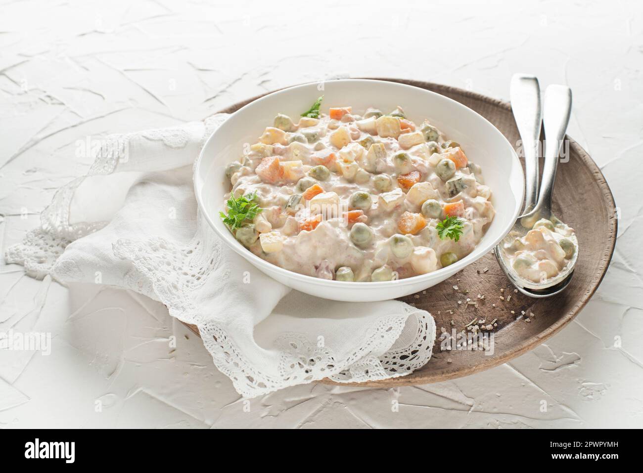 Ciotola di insalata russa olivier insalata francese con verdure e uova condite con maionese su tavolo bianco Foto Stock