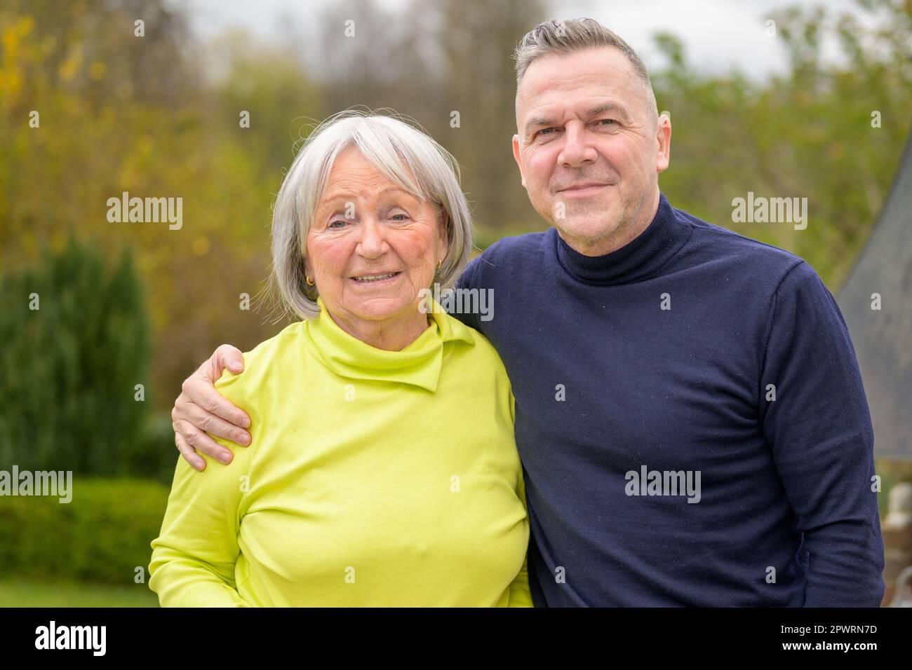 Famiglia di due generazioni, madre e figlio si tengono in braccio e sembrano amichevoli nei confronti della fotocamera Foto Stock