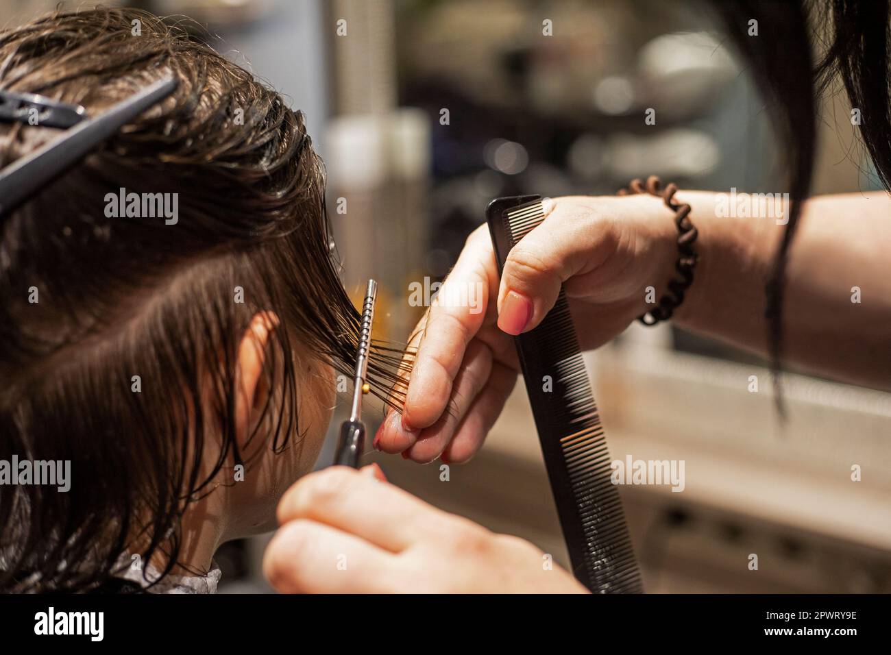barbershoper taglia i capelli puliti bagnati sotto un coltello e pettine ad un adolescente Foto Stock