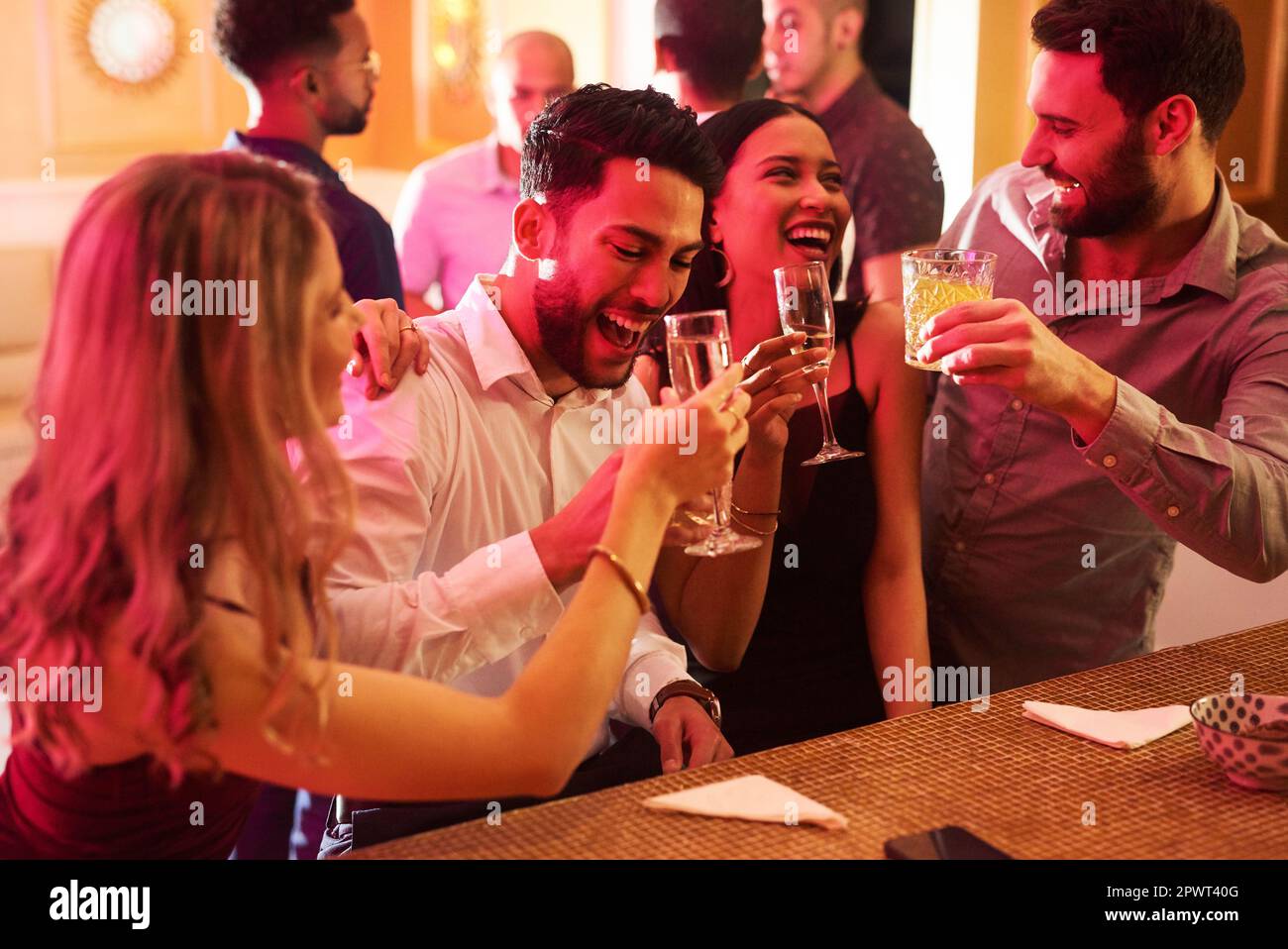 Lascia ottenere folle. un gruppo di giovani amici allegri che brinda con un drink all'interno di un bar la sera Foto Stock