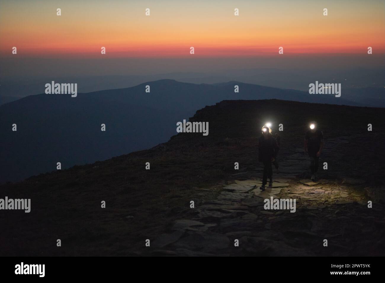 Persone che camminano di notte per vedere l'alba. Montagne all'alba. Uomo in piedi sul picco. Paesaggio naturale di montagna con cime nebbie illuminate, nebbia slop Foto Stock