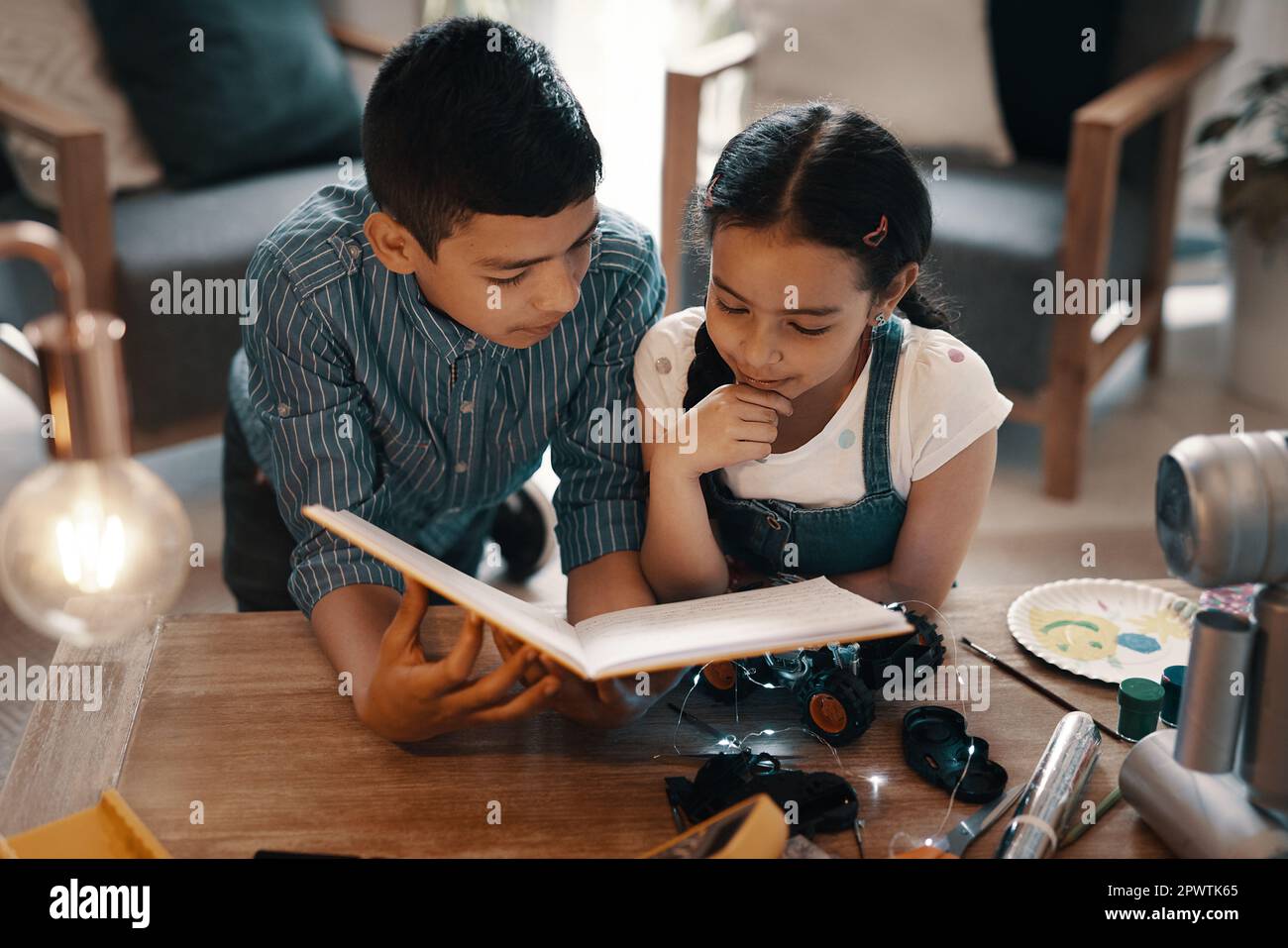 Erano entrambi entusiasti e interessati alla robotica. due adorabili fratelli e sorelle che leggono un libro sulla robotica insieme a casa Foto Stock
