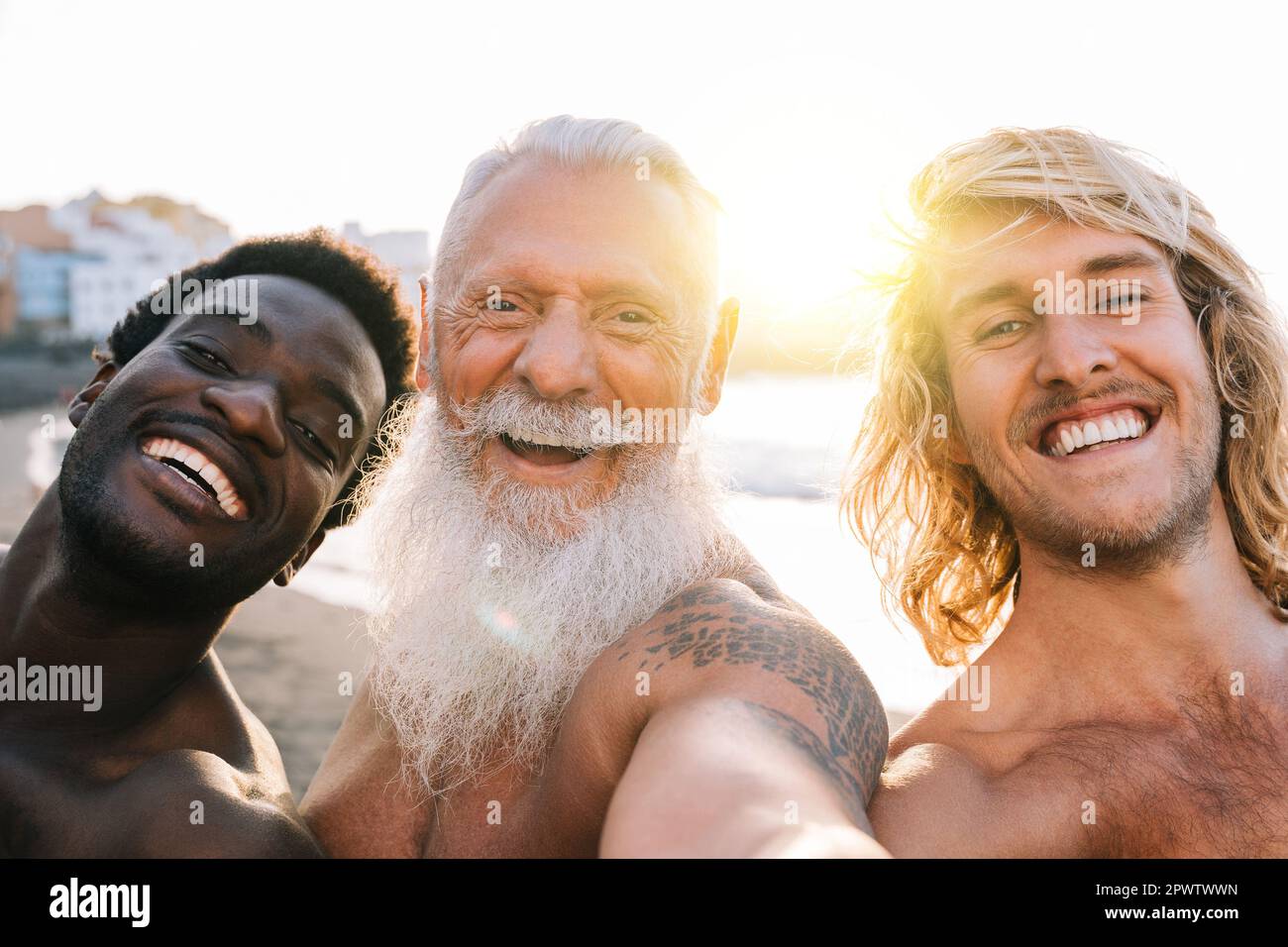 Amici multigenerazionali felici che prendono selfie sulla spiaggia - amici maschili multirazziali che si divertono durante le vacanze estive - stile di vita di viaggio di vacanza Foto Stock