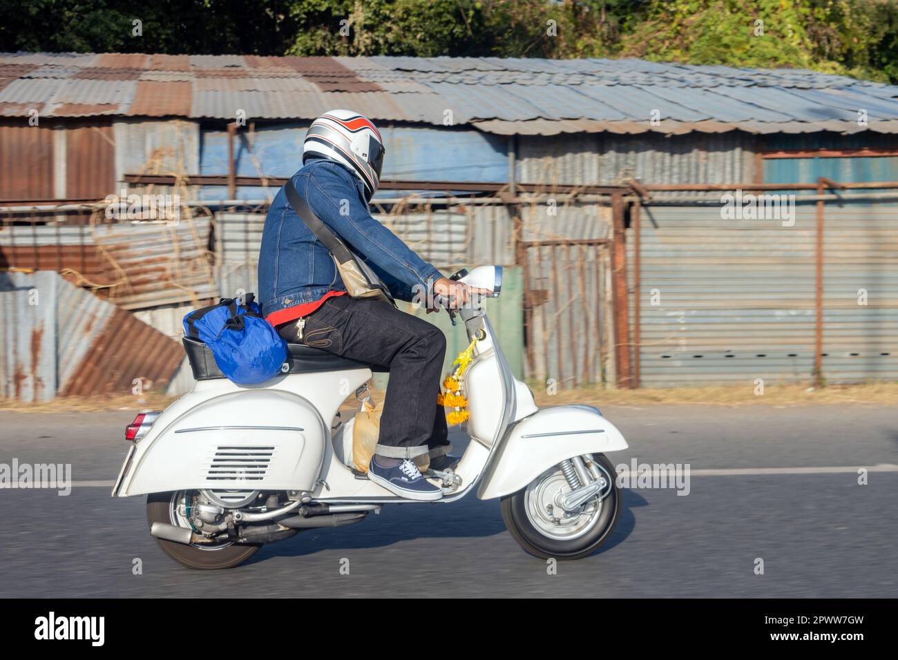 Un uomo che guida uno scooter retrò in un turno, Thailandia Foto Stock