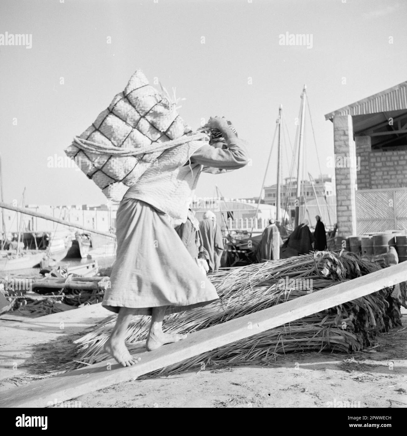 Un uomo che carica un pacchetto su una barca fluviale a Riyadh, Arabia Saudita, 1952 Foto Stock