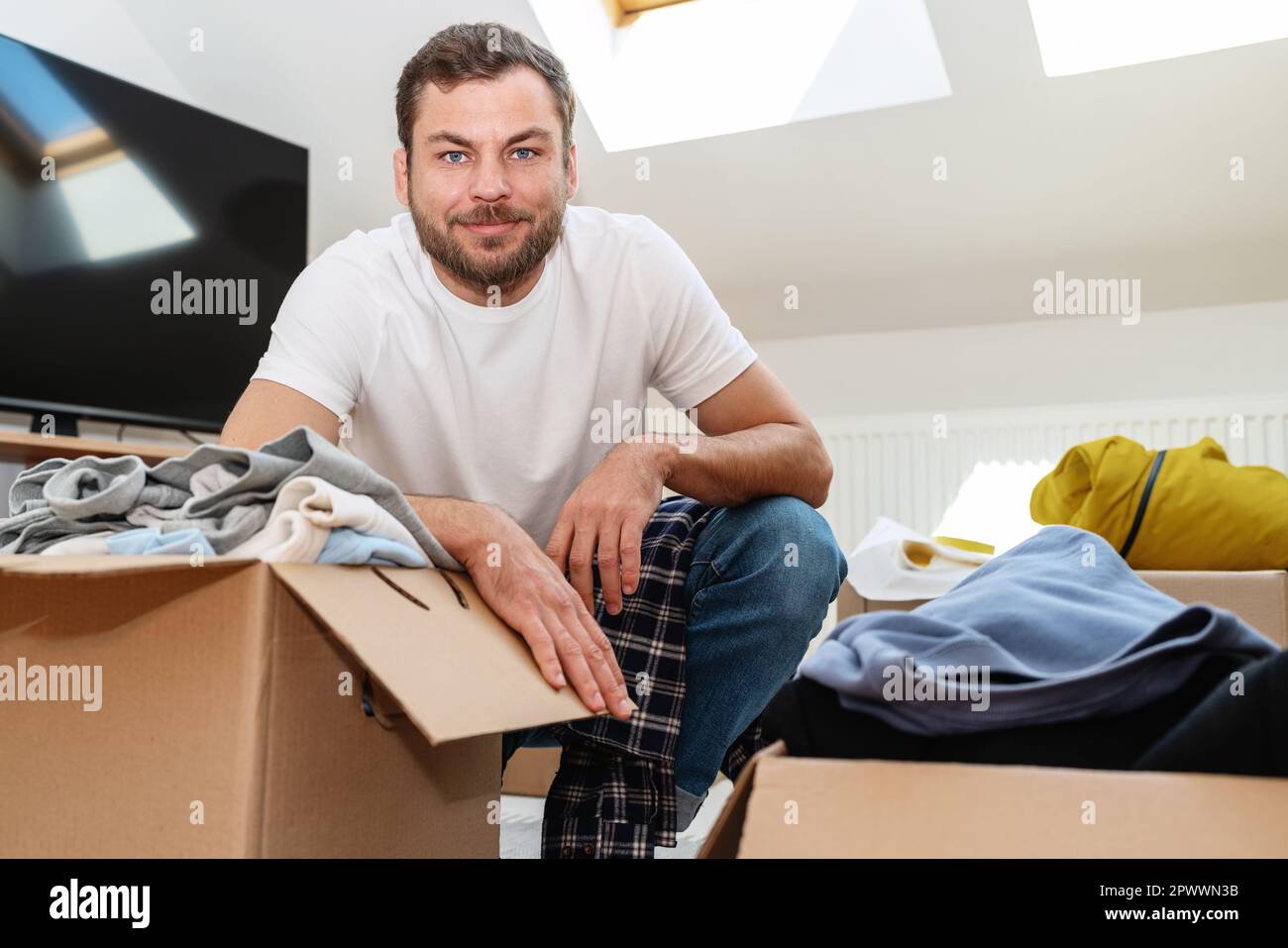Volontario uomo che lavora a casa confezionare vestiti in cartoncini per la donazione. Foto Stock