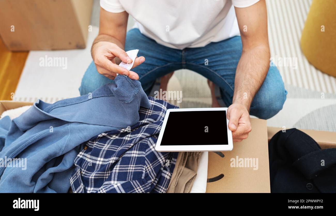 Uomo inventario abbigliamento del suo ordine Internet dal negozio online utilizzando tablet digitale. Foto Stock