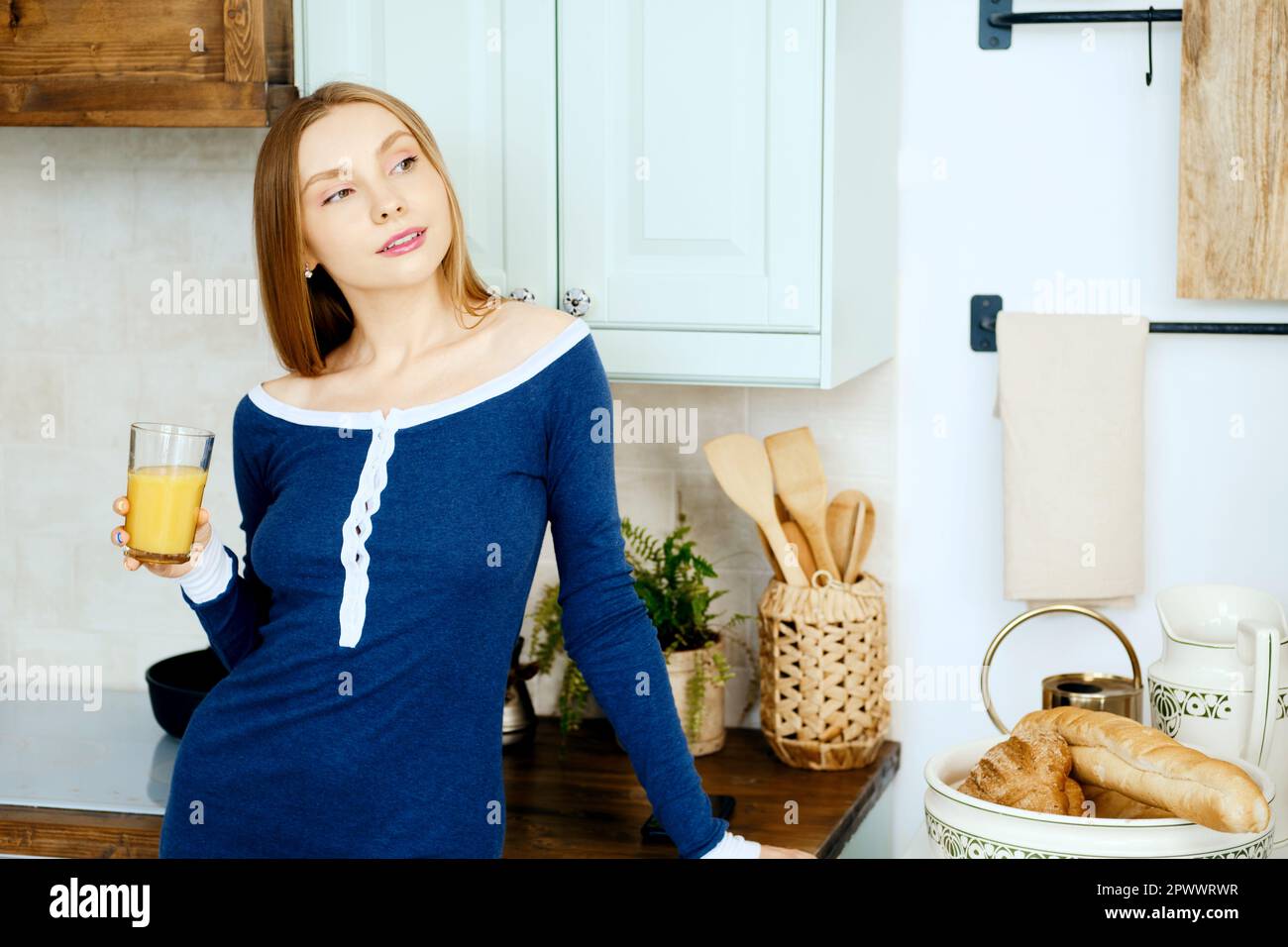 Donna sognante in cucina con bicchiere di succo Foto Stock