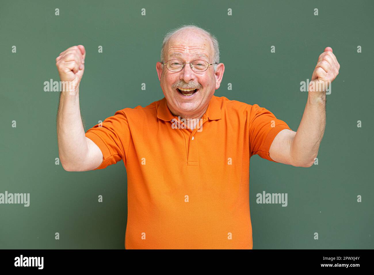 Ritratto di felice uomo anziano dai capelli grigi con baffi che indossa occhiali con le braccia sollevate Foto Stock