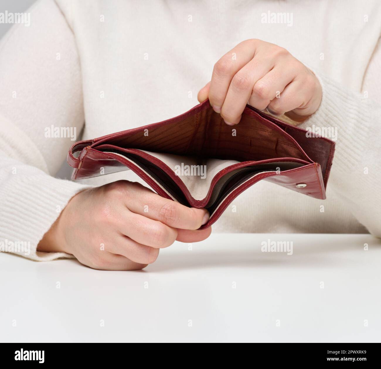 Due mani femminili tengono un portafoglio vuoto in pelle marrone, povertà Foto Stock
