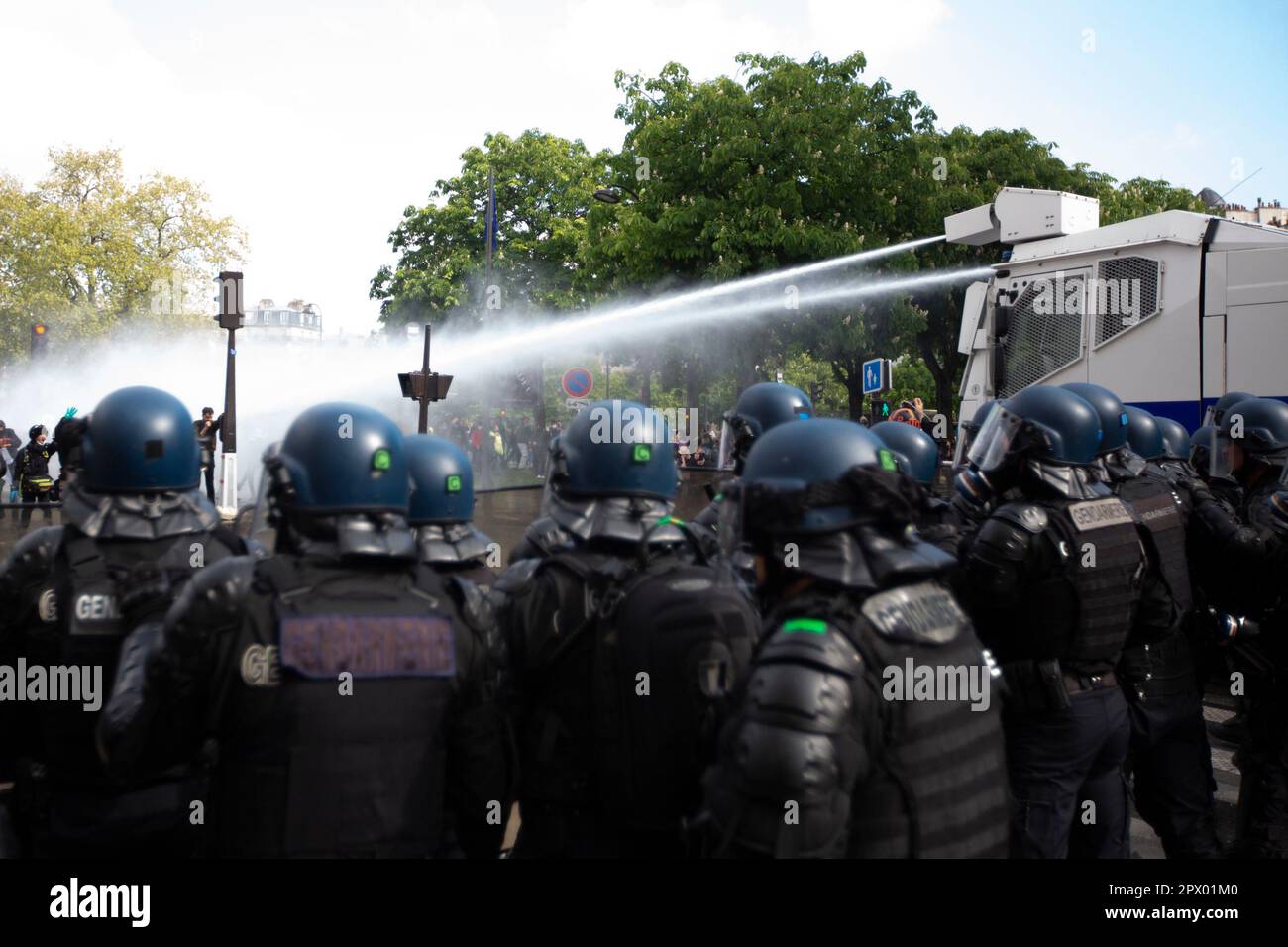 Manifestanti e polizia francese si scontrano durante le rivolte di Mayday il 1 maggio 2023 nel centro di Parigi. Molte persone si presentarono per esprimere la loro antipatia verso il presidente Macron e le sue attuali politiche. Immaginate i cannoni ad acqua della polizia francese osservati da diversi agenti di polizia antisommossa. Foto Stock