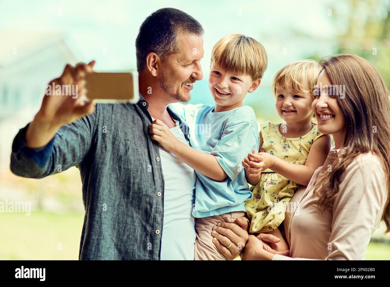 Tutti pronti sorriso. una giovane famiglia felice che prende selfie insieme all'aperto Foto Stock