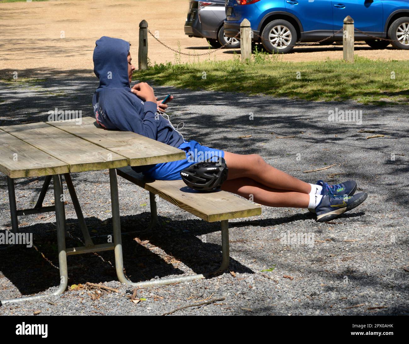 Un giovane che indossa una felpa con cappuccio usa il suo smartphone in un parco pubblico di Abingdon, Virginia. Foto Stock