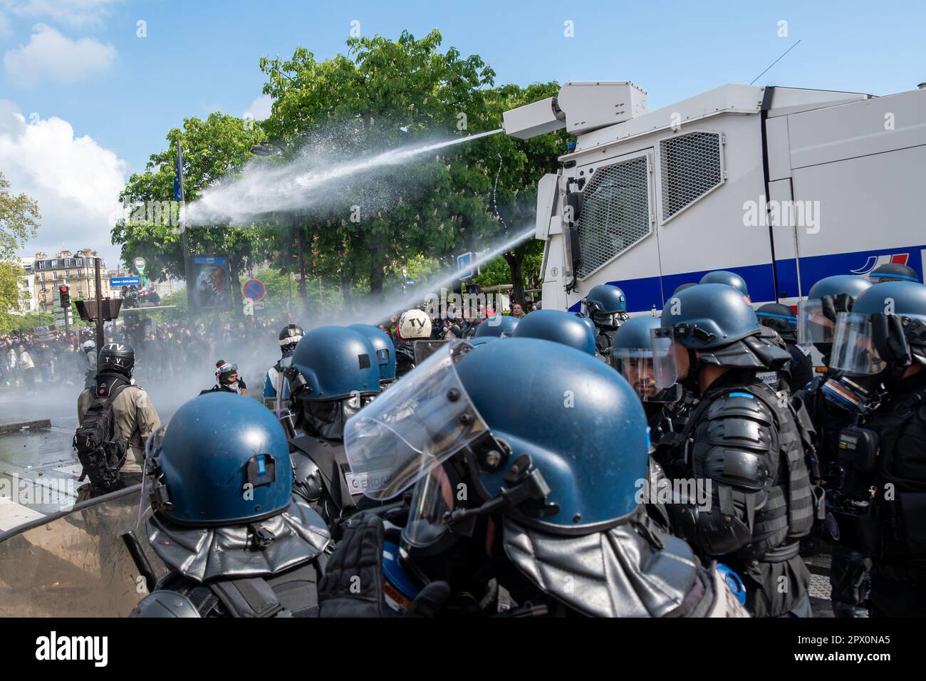 Il cannone ad acqua della polizia francese scortato da gendarmi in attrezzature antisommossa che inculano i dimostranti alla fine di una protesta contro la riforma pensionistica Foto Stock
