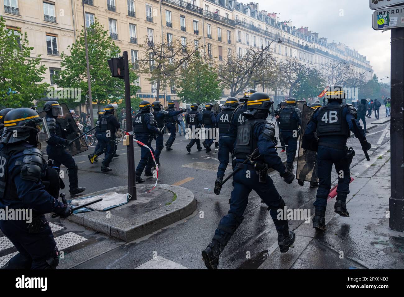 La polizia antisommossa francese del CRS accusando i violenti manifestanti di batoni durante una manifestazione contro la riforma pensionistica del governo in una strada di Parigi Foto Stock