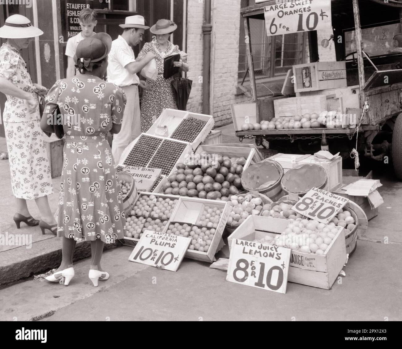 1930S TRE DONNE CASALINGHE CHE COMPRANO FRUTTI E BACCHE DA UN UOMO E DA UN RAGAZZO CONTADINI CON PICK-UP CAMION PARCHEGGIATO IN CITTÀ CORDOLO - M6467 PAL001 HARS B&W PARCHEGGIATO ABITI SHOPPER ACQUIRENTI PICK-UP AFROAMERICANI AFROAMERICANI E AGRICOLTORI ETNICITÀ NERA CASALINGHE CITTÀ CORDOLO ACQUISTO FRUTTI DI BACCHE NERO E BIANCO ETNICITÀ CAUCASICA CONVENIENZA TALLONI ALTI AFROAMERICANI VECCHIO STILE Foto Stock