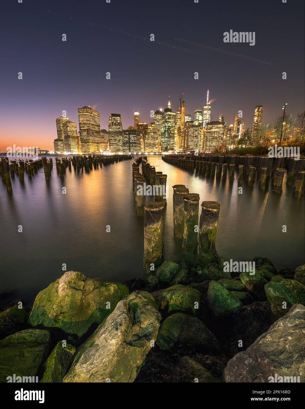 Vista di Lower Manhattan al crepuscolo vista da Brooklyn. Il resto di un vecchio molo può essere visto in primo piano e lo skyline della città sullo sfondo Foto Stock