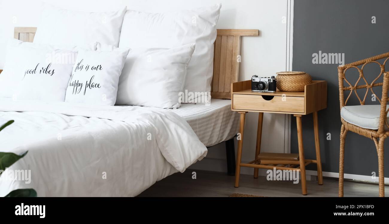 Comodino in legno con fotocamera e cestino in vimini in camera da letto  luminosa Foto stock - Alamy