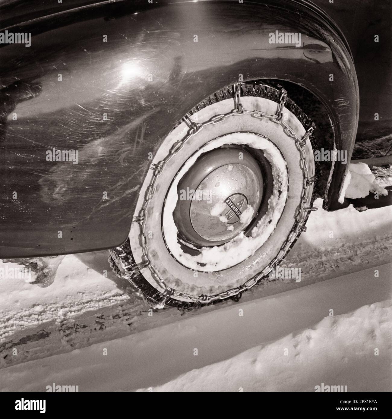 1930S PRIMO PIANO DELLE CATENE DA NEVE SUL PNEUMATICO DI UNA VETTURA OLDSMOBILE CHE FORNISCE UNA MAGGIORE TRAZIONE DURANTE LA GUIDA IN INVERNO NEVE E GHIACCIO - M6370 HAR001 HARS VECCHIO STILE Foto Stock