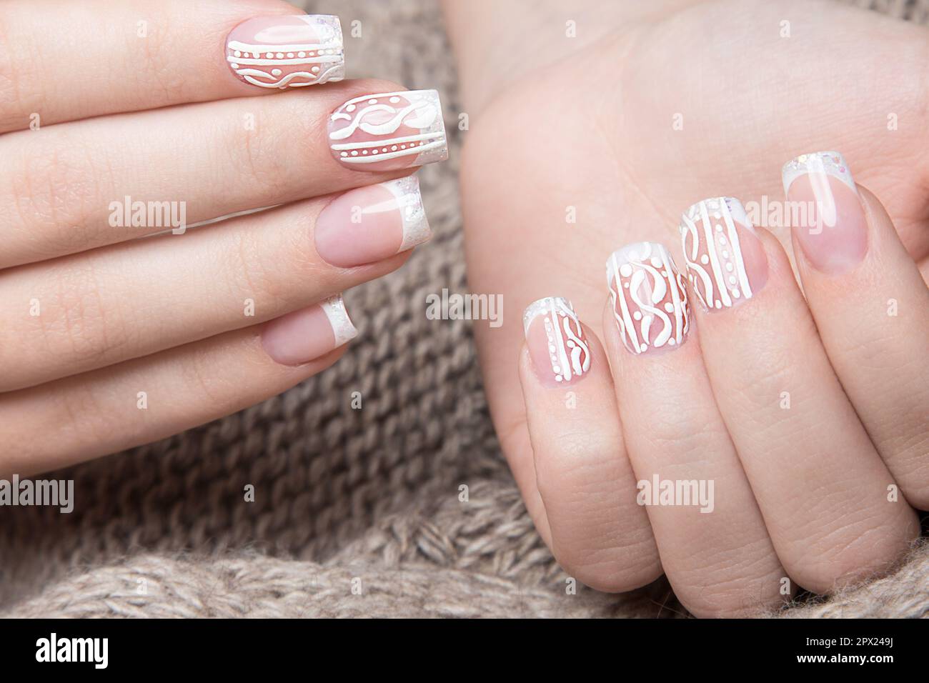 Manicure bianco neve sulle mani femminili. Design delle unghie invernali. Foto scattata in studio su uno sfondo di lana. Foto Stock