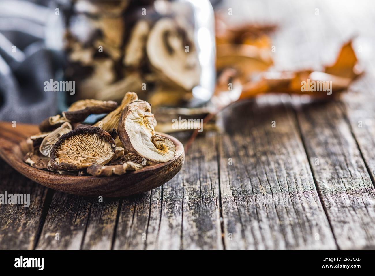 Funghi secchi tagliati a fette in un cucchiaio di legno sul tavolo di legno. Foto Stock