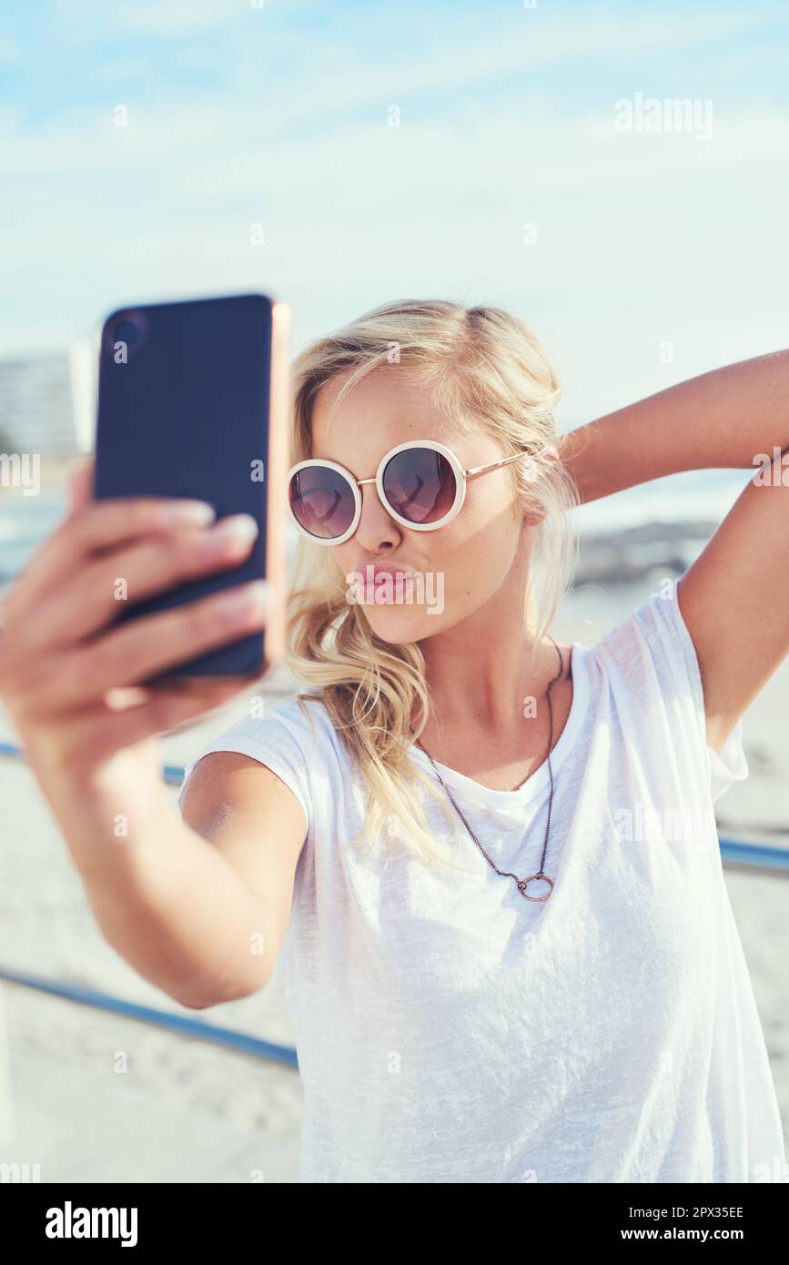 I selfie estivi sono i miei preferiti. una giovane donna che prende un selfie mentre passa la giornata in riva al mare Foto Stock