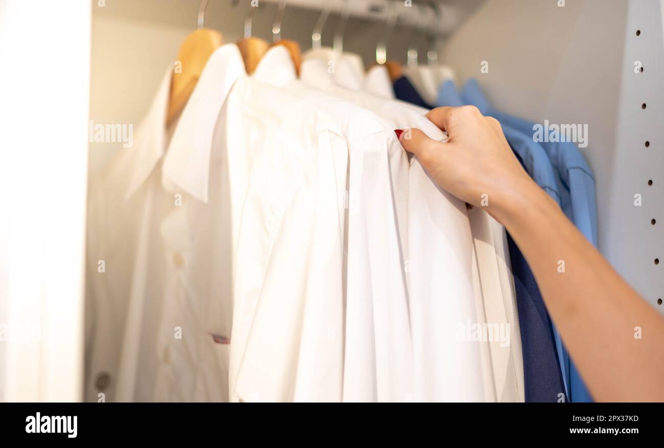 Donna scelta di vestiti per il motivo controllato polo in cotone sul rack in negozio di stoffa in un grande magazzino. Controllare il prezzo e lo sconto. Foto Stock