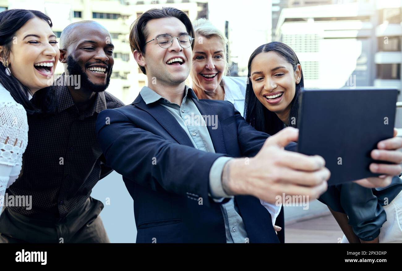 Facciamo il lavoro di sogno. un gruppo di colleghi aziendali che scattano selfie con un tablet all'esterno Foto Stock