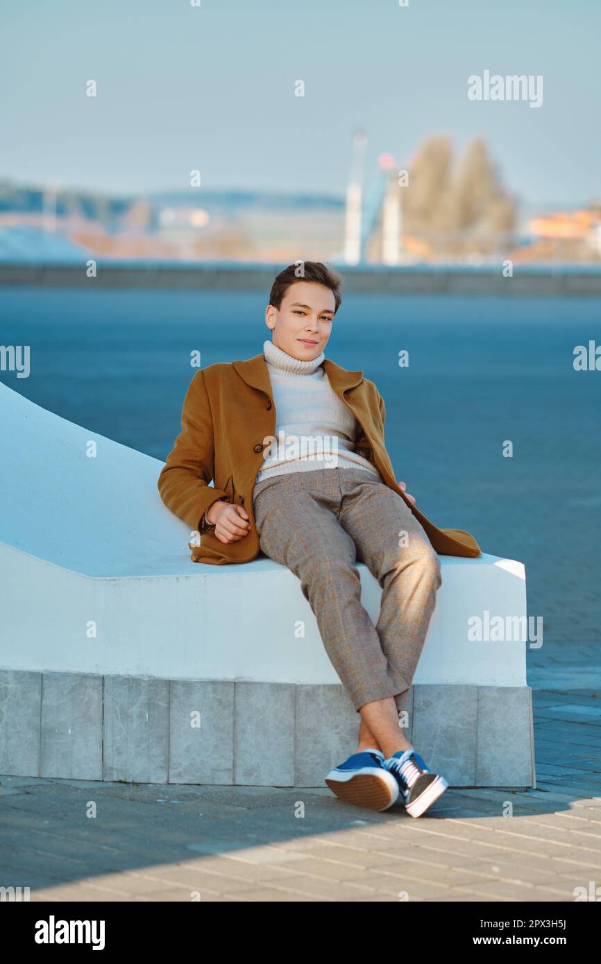 Abbigliamento primavera - autunno. Street fashion. Giovane uomo in pantaloni a scacchi, maglione e cappotto di lana. Foto Stock
