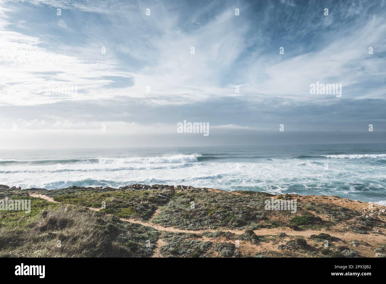 Costa con l'oceano atlantico a Cascais, Portogallo. Onde sulla riva e colline rocciose Foto Stock