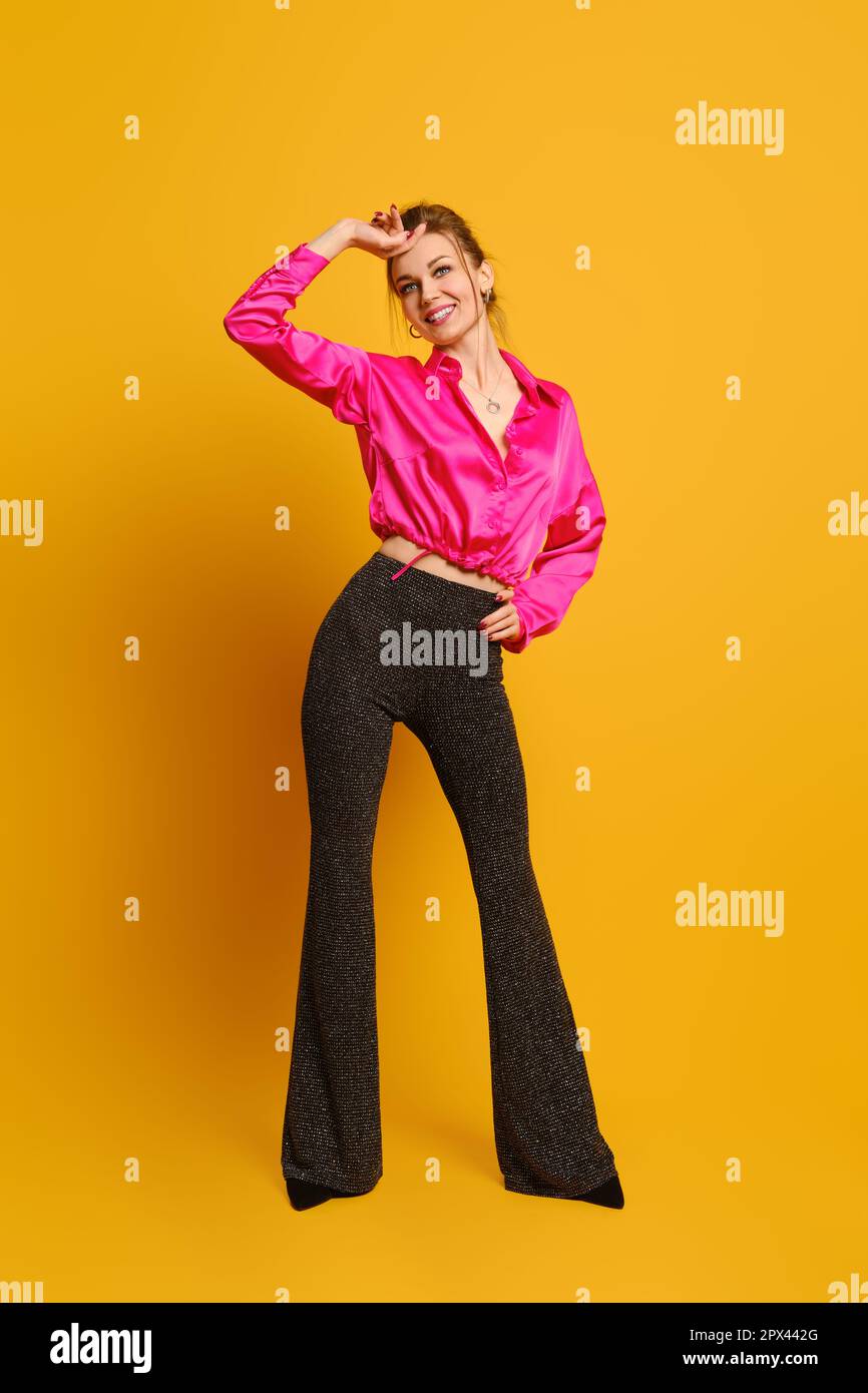 Donna gioiosa in blusa maroon e pantaloni svasati con glitter Foto Stock