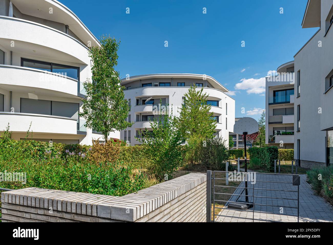 Moderni edifici di appartamenti appena rifiniti con case a castello in una nuova area di sviluppo con tempo soleggiato e cielo blu Foto Stock