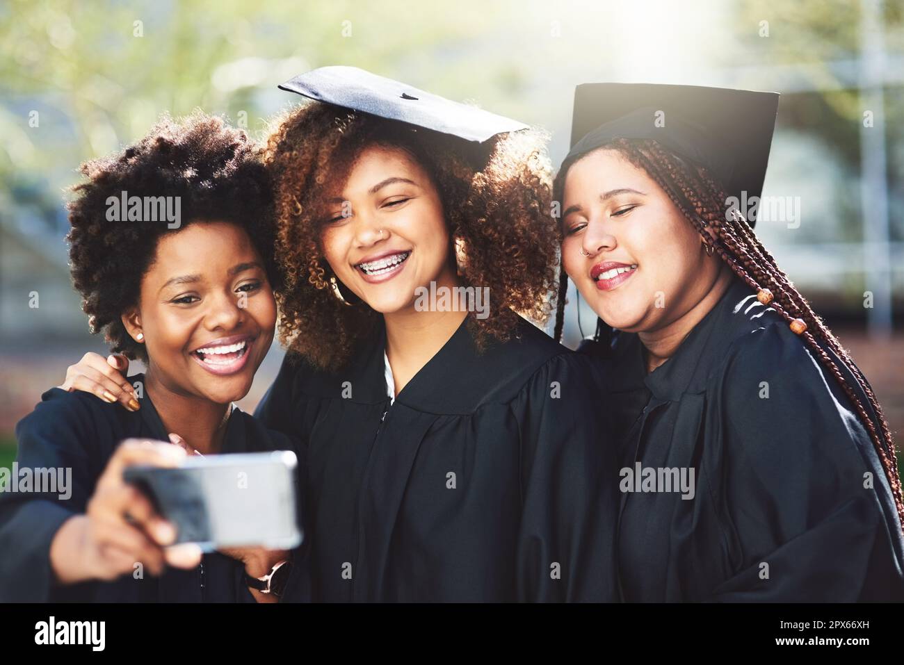 Obiettivi della squadra. tre studenti che prendono un selfie il giorno della laurea Foto Stock