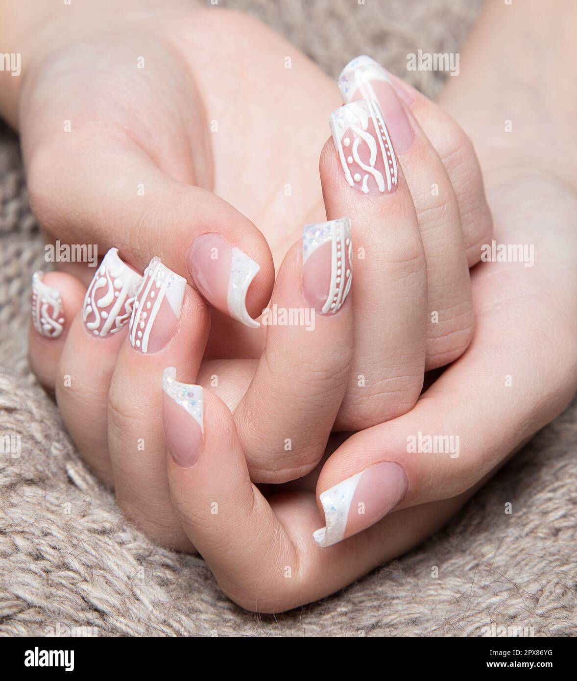 Manicure bianco neve sulle mani femminili. Design delle unghie invernali. Foto scattata in studio su uno sfondo di lana. Foto Stock