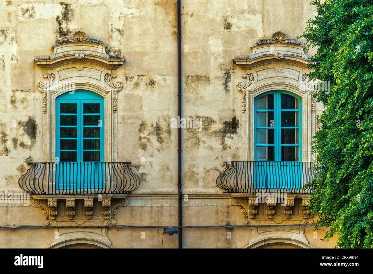 Due finestre blu con decorazioni barocche su un antico edificio della città di noto. Noto, provincia di Siracusa, Sicilia, Italia, Europa Foto Stock