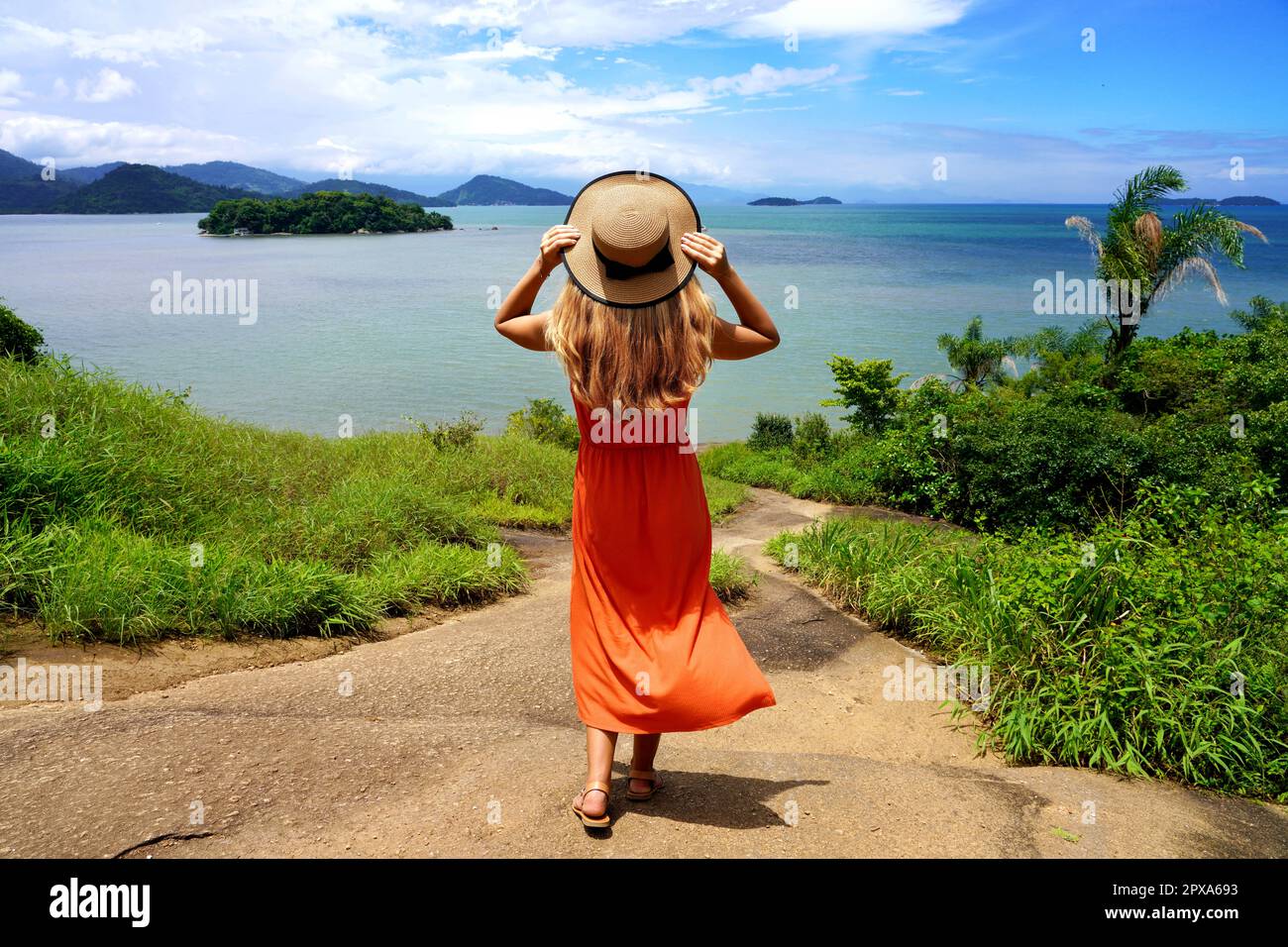 Bella ragazza con abito estivo arancione reggicaletto godendo di vista sulla Costa Verde, Brasile Foto Stock