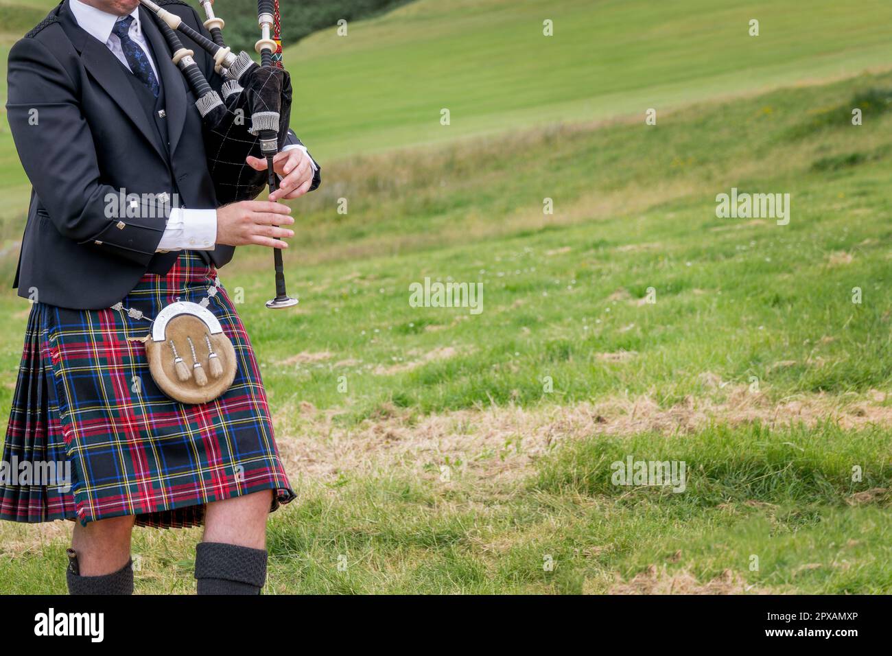 Bagpiper scozzese vestito in kilt tradizionale nelle Highlands della Scozia (con spazio per le copie) Foto Stock
