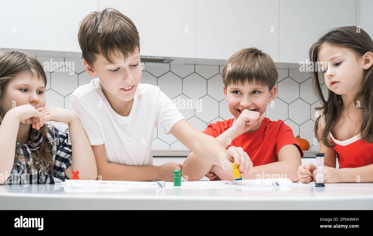 Ritratto di gruppo di amici sorridenti bambini seduti a un tavolo bianco in  cucina, gioco da tavolo tavolo da gioco, movimento di figure colorate su  tavola bianca w Foto stock - Alamy